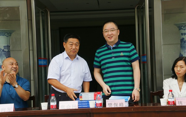 新乡市牧野区税务局党委书记、局长樊保峰向乐竞(中国)党委书记张会民赠送税法知识书籍.jpg